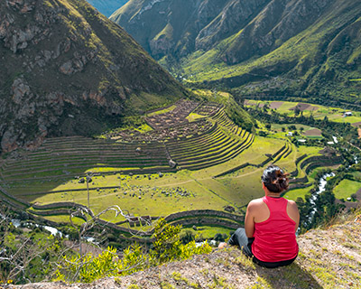 Woman resting and watching Patallaqta archaeological site from a mountain