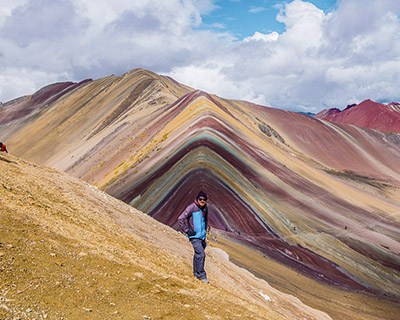 Woman taking a picture with the panoramic view of Rainbow Mountain