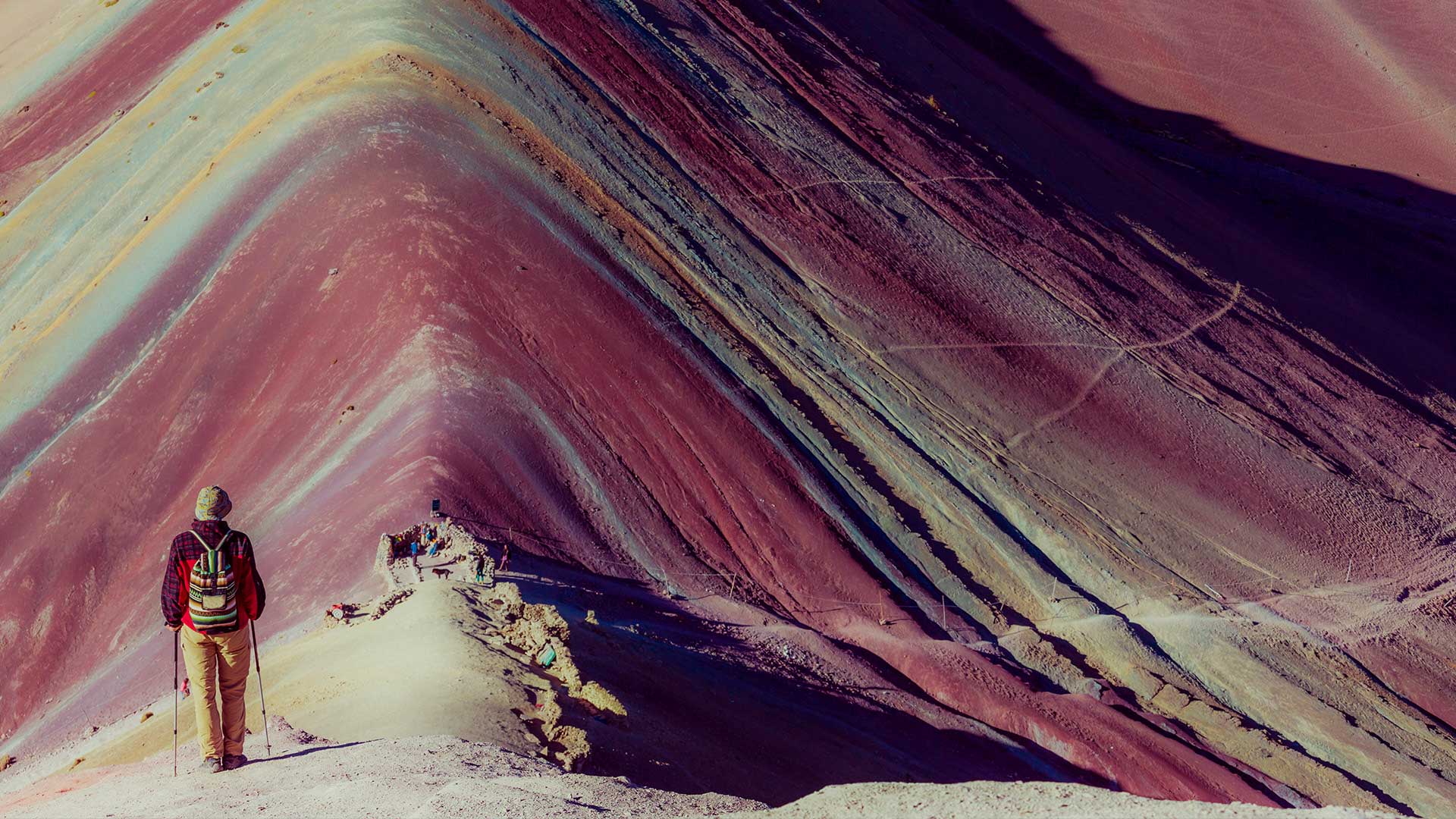 Tourist walking in the direction of the rainbow mountain with its intense colors
