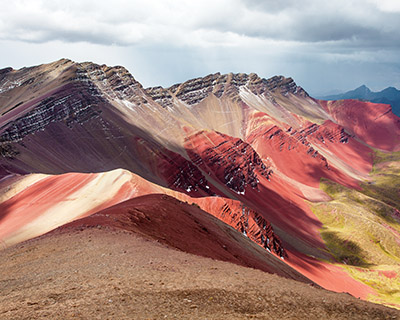 Woman in an Andean poncho with panoramic view of Rainbow Mountain