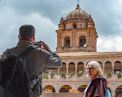 Man is taking a photograph of his wife with the view of the dome of the Santo Domingo temple